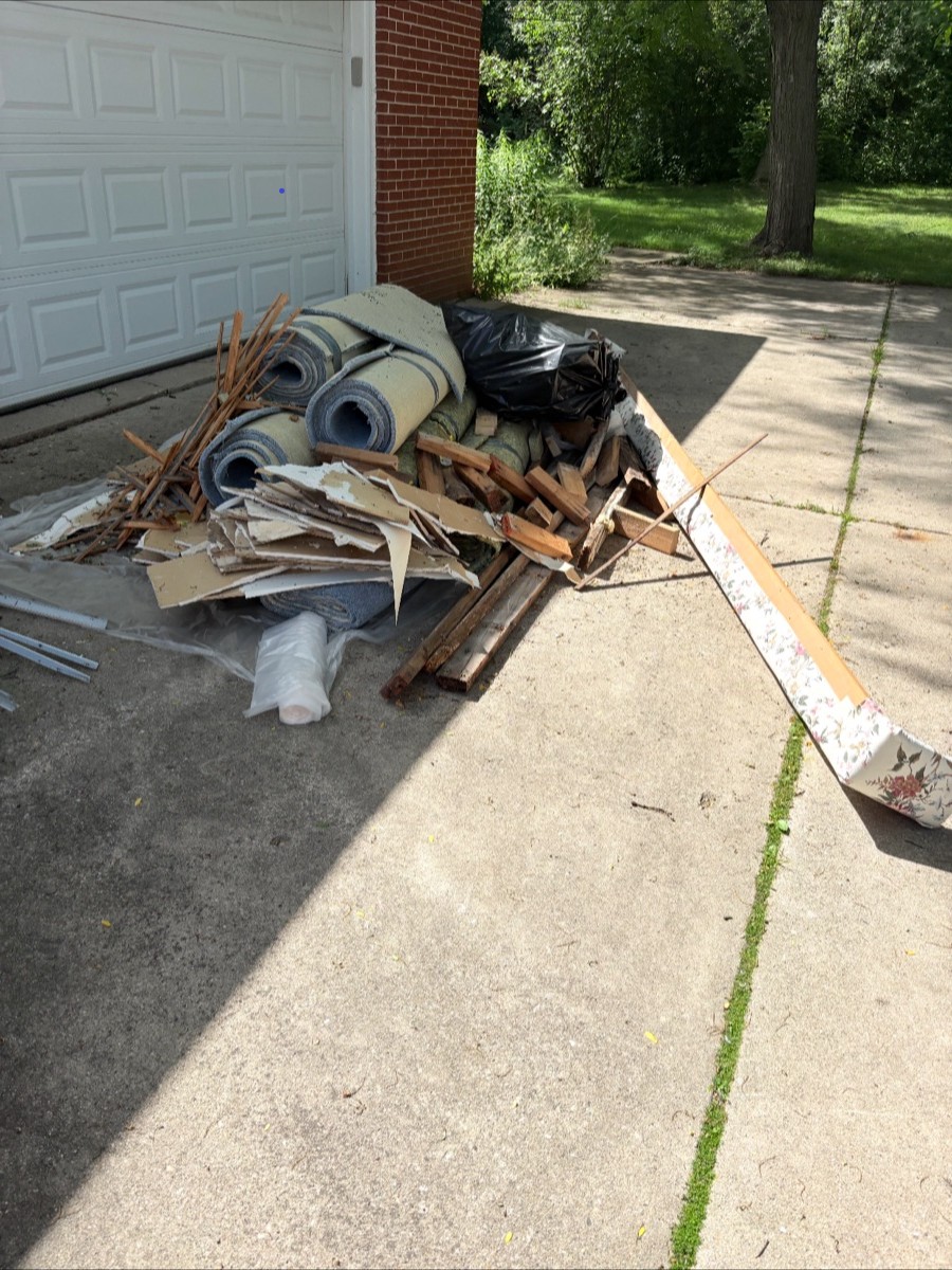 A driveway piled with old carpet, wood, and debris before TT's Junk Removal cleared it